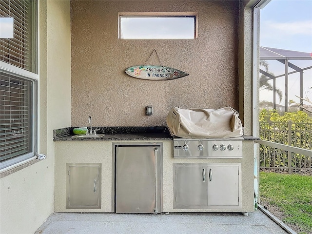 view of patio featuring glass enclosure, area for grilling, and sink