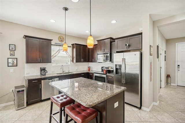 kitchen featuring a breakfast bar, a center island, sink, hanging light fixtures, and appliances with stainless steel finishes