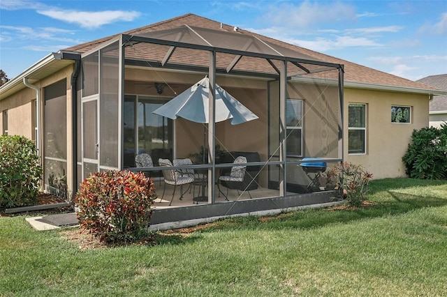 back of property with glass enclosure, a patio, and a lawn