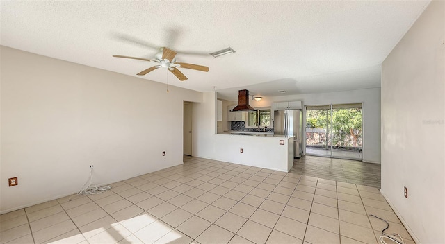 unfurnished living room featuring ceiling fan, light tile patterned floors, and a textured ceiling