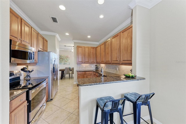 kitchen with dark stone counters, a breakfast bar, kitchen peninsula, and appliances with stainless steel finishes