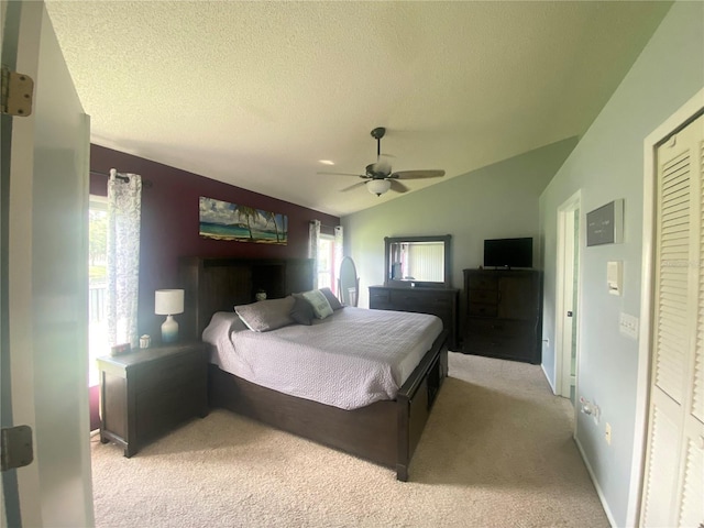 carpeted bedroom featuring a textured ceiling, a closet, vaulted ceiling, and ceiling fan