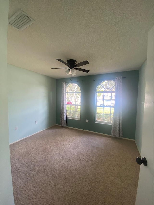 carpeted empty room featuring ceiling fan and a textured ceiling