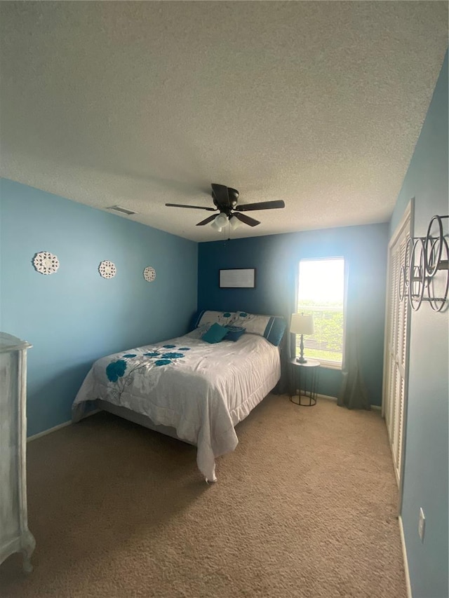 carpeted bedroom with ceiling fan and a textured ceiling