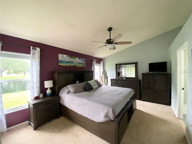 bedroom featuring light colored carpet, multiple windows, lofted ceiling, and ceiling fan