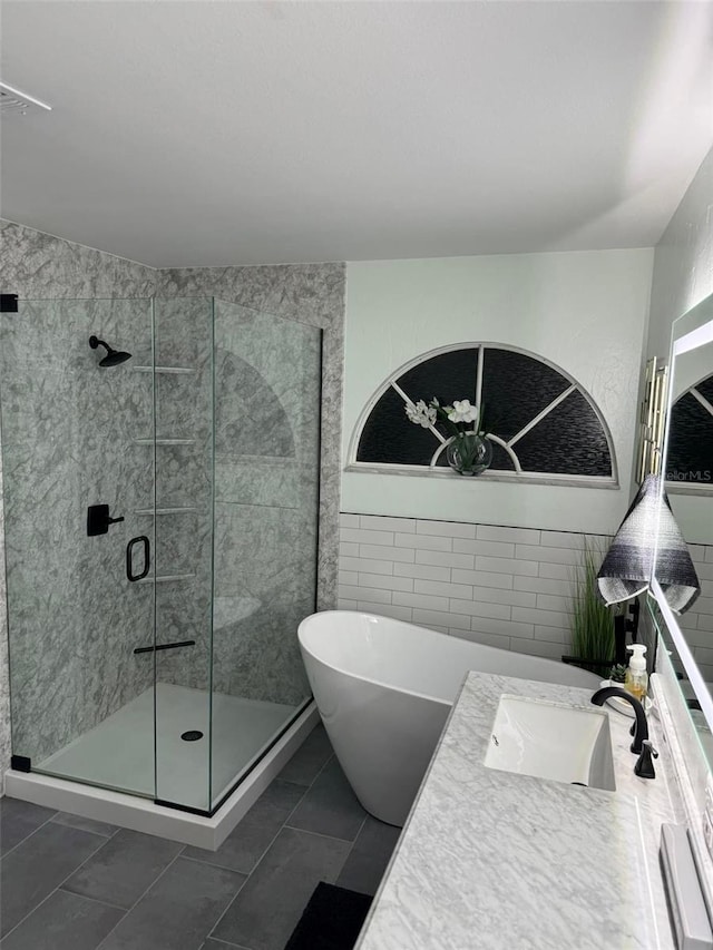 bathroom featuring tile patterned floors, vanity, tile walls, and shower with separate bathtub