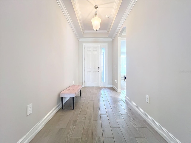 entrance foyer with light hardwood / wood-style flooring, a raised ceiling, and crown molding