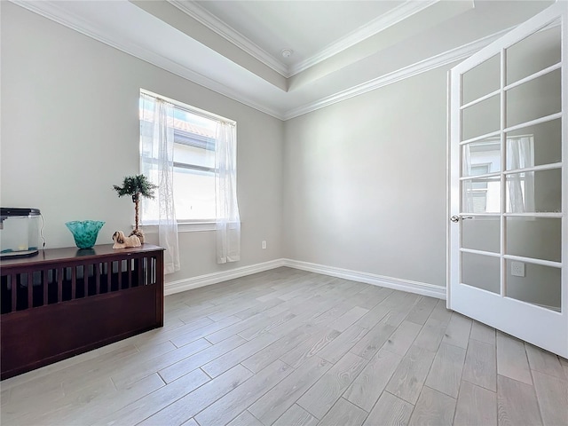 spare room featuring light hardwood / wood-style flooring, crown molding, and a tray ceiling