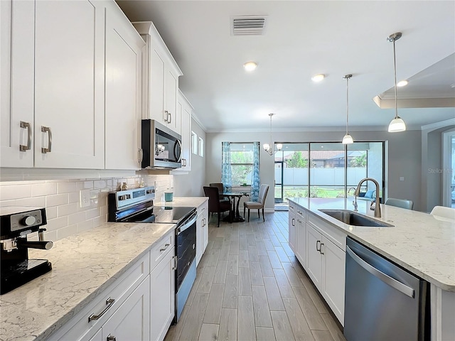 kitchen featuring white cabinets, stainless steel appliances, pendant lighting, and sink