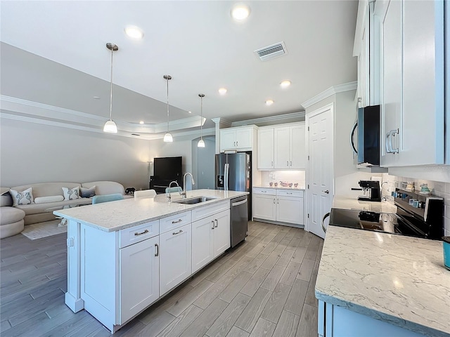 kitchen with hanging light fixtures, sink, a kitchen island with sink, white cabinetry, and stainless steel appliances