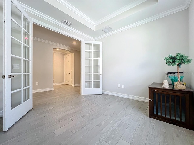 empty room featuring ornamental molding, light wood-type flooring, and french doors