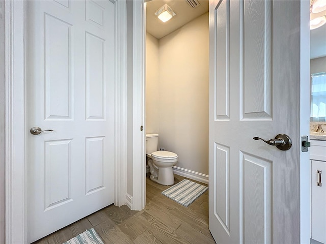 bathroom with wood-type flooring, vanity, and toilet