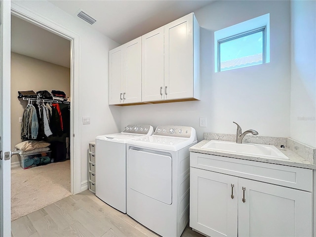 washroom featuring cabinets, light hardwood / wood-style floors, sink, and washing machine and clothes dryer