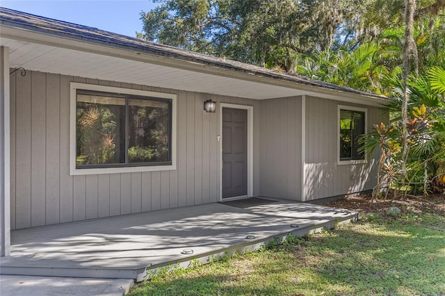 entrance to property with a wooden deck and a lawn