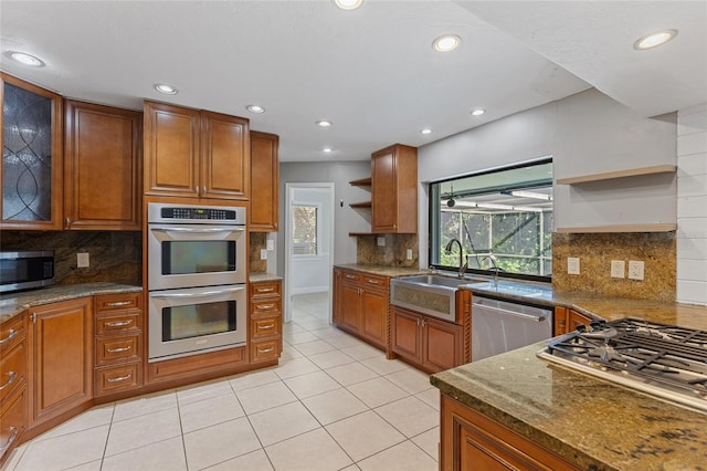 kitchen with light tile patterned floors, stainless steel appliances, sink, and stone countertops