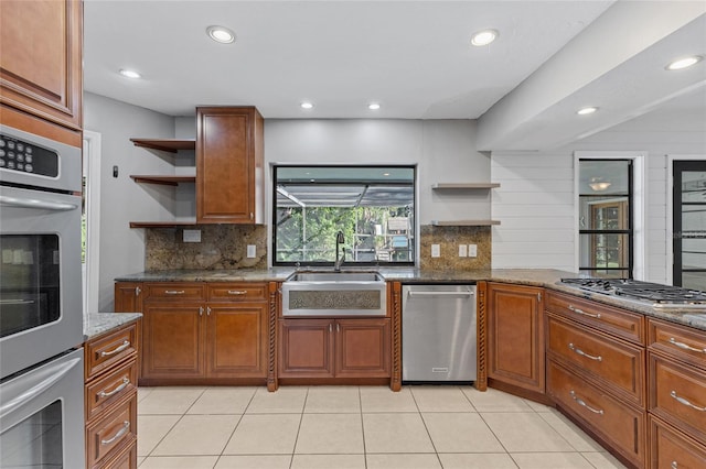 kitchen featuring light stone countertops, stainless steel appliances, wood walls, and light tile patterned floors