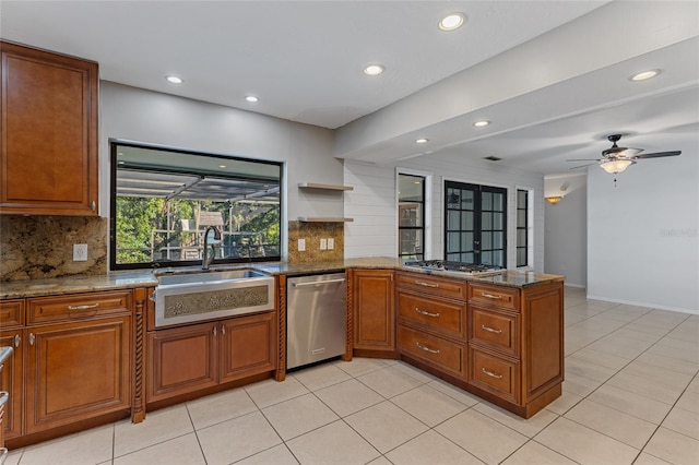 kitchen with appliances with stainless steel finishes, dark stone counters, kitchen peninsula, and ceiling fan