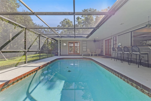 view of swimming pool featuring ceiling fan, french doors, a patio area, a bar, and a lanai