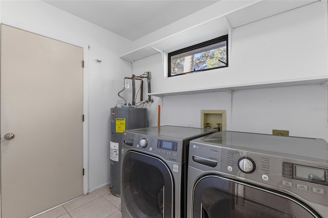 washroom with washer and clothes dryer, electric water heater, and light tile patterned floors