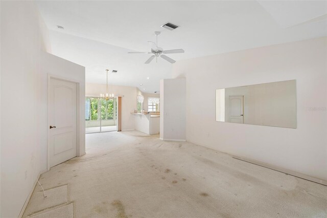 carpeted spare room with ceiling fan with notable chandelier