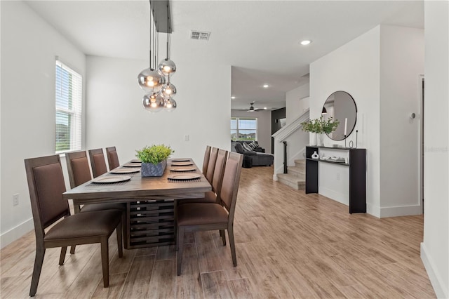 dining space with ceiling fan with notable chandelier, light hardwood / wood-style flooring, and plenty of natural light