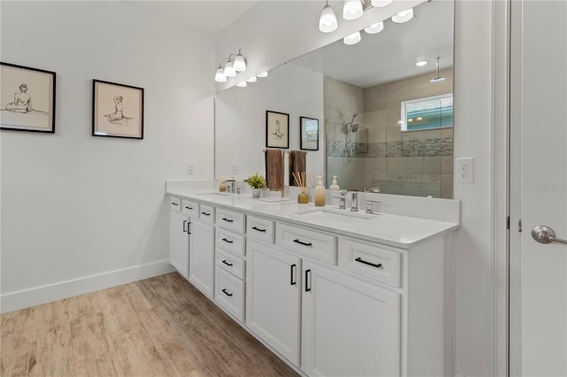 bathroom with wood-type flooring, vanity, and a tile shower