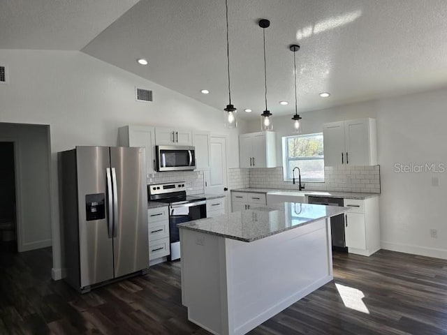 kitchen featuring a center island, dark hardwood / wood-style floors, white cabinets, lofted ceiling, and stainless steel appliances