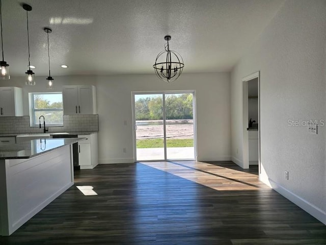 kitchen with pendant lighting, white cabinetry, a notable chandelier, dark hardwood / wood-style flooring, and decorative backsplash