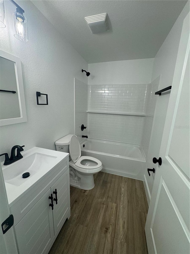 full bathroom with vanity, bathtub / shower combination, wood-type flooring, a textured ceiling, and toilet