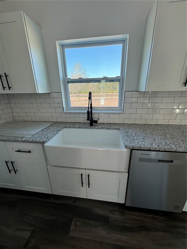 kitchen with light stone countertops, white cabinetry, decorative backsplash, and stainless steel dishwasher