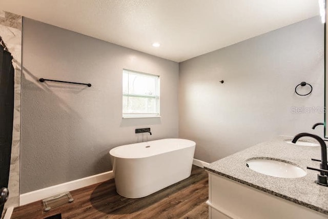 bathroom with vanity, hardwood / wood-style flooring, and a bathtub