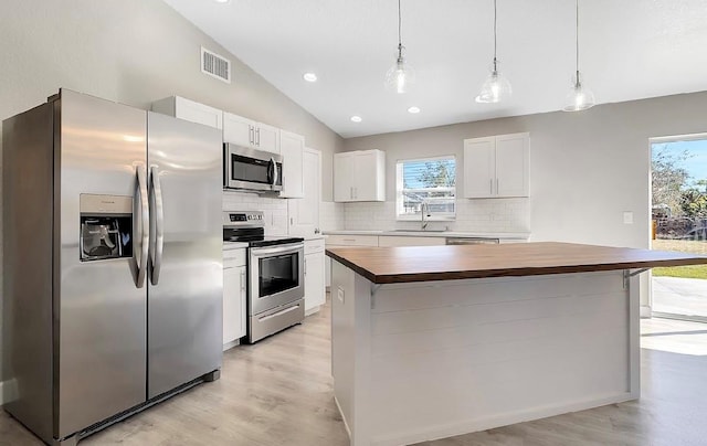 kitchen with appliances with stainless steel finishes, white cabinetry, wood counters, and a kitchen island