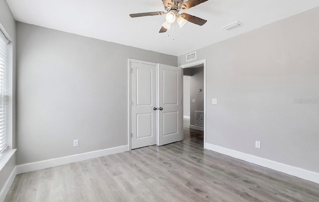 unfurnished bedroom with light wood-type flooring, ceiling fan, and a closet