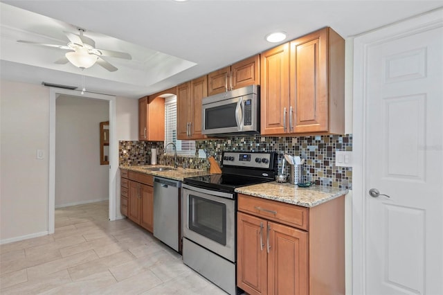 kitchen featuring ceiling fan, sink, tasteful backsplash, stainless steel appliances, and light stone countertops