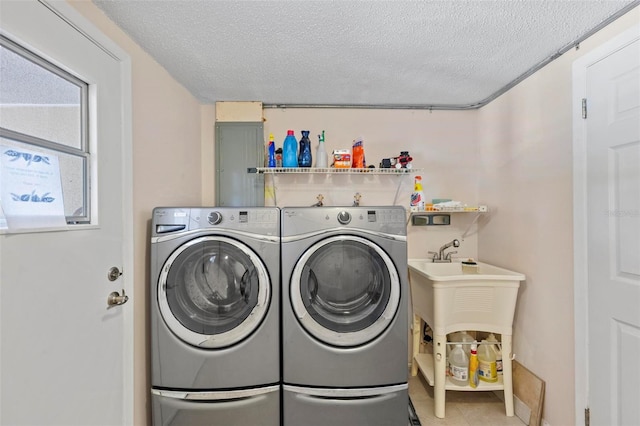 laundry area featuring a textured ceiling, electric panel, and washing machine and dryer