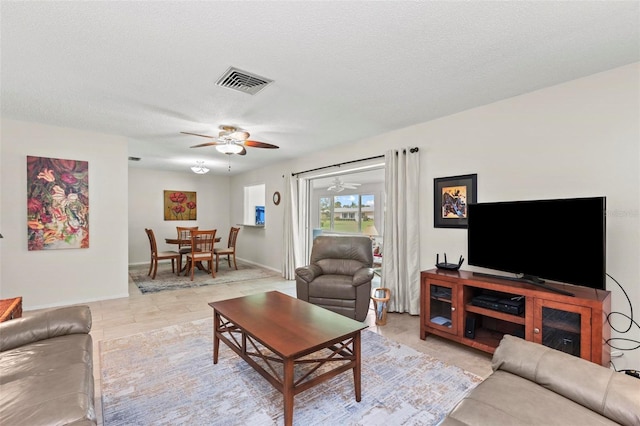 living room with ceiling fan, light tile patterned floors, and a textured ceiling