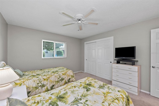 bedroom featuring a textured ceiling, light carpet, ceiling fan, and a closet