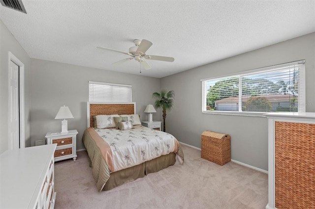 carpeted bedroom featuring ceiling fan and a textured ceiling