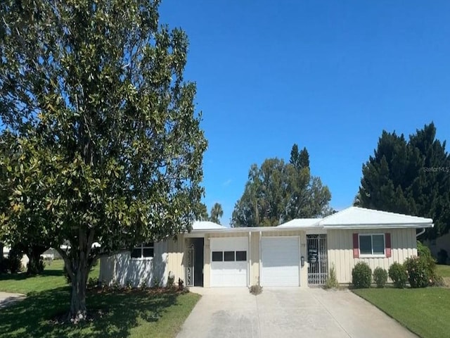 single story home featuring a garage, concrete driveway, and a front lawn