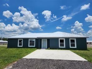 view of front of house with a front yard, metal roof, and driveway
