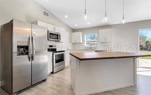 kitchen featuring visible vents, appliances with stainless steel finishes, light wood-style floors, white cabinetry, and vaulted ceiling