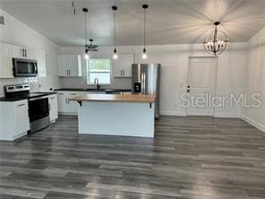 kitchen with appliances with stainless steel finishes, white cabinetry, a center island, and vaulted ceiling