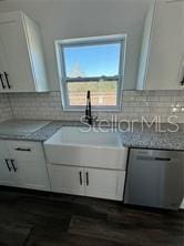 kitchen featuring decorative backsplash, stainless steel dishwasher, light stone countertops, and white cabinets