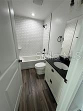 full bath featuring shower / bath combination, vanity, toilet, and wood finished floors