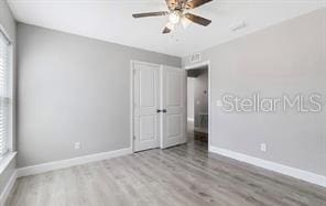 unfurnished bedroom featuring wood finished floors, baseboards, and multiple windows