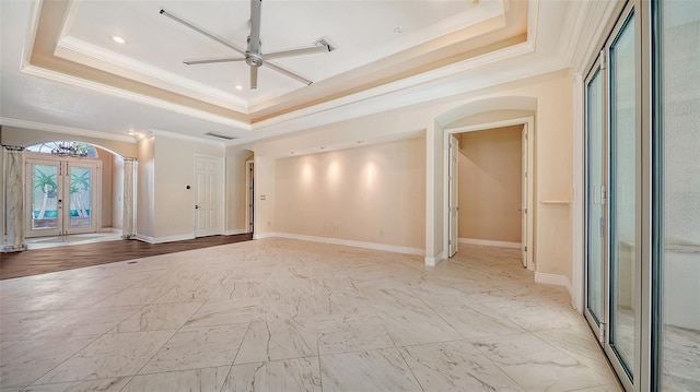 unfurnished living room with a tray ceiling, ceiling fan, and french doors