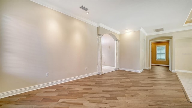 empty room with ornate columns, light hardwood / wood-style floors, and crown molding