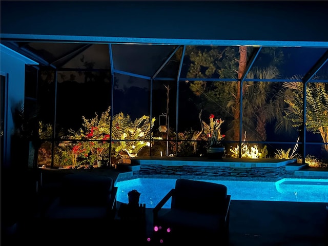 pool at twilight featuring glass enclosure and a patio