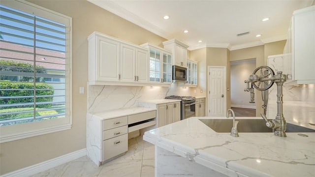 kitchen with light stone counters, white cabinets, appliances with stainless steel finishes, and plenty of natural light