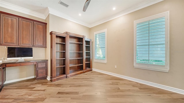 unfurnished office featuring light hardwood / wood-style flooring, built in desk, crown molding, and a healthy amount of sunlight